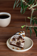 Piece of Pancho cake with pineapple and sour cream topped with chocolate biscuit and walnut and cup of coffee. Vegan dessert. Sugar, lactose and gluten free. Vertical orientation.