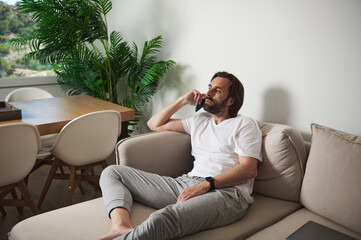 Man Relaxing at Home While Talking on Phone in Minimalist Interior