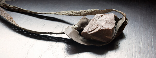 Sling with stone on wooden background