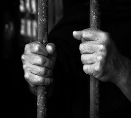 Hands holding the cage of jail