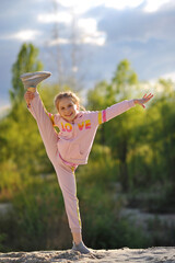 Funny kid playing and doing splits outdoor on nature in the summer. Active child girl doing yoga exercise. Copy space for text. Happy childhood