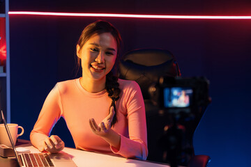 Smiling creative young beautiful Asian influencer recording on camera with positive podcast speech...
