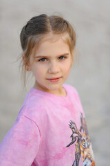 Portrait of smiling child girl with green eyes and braided hair in pink t-shirt posing outdoor in the summer. Beautiful children. Natural kid beauty