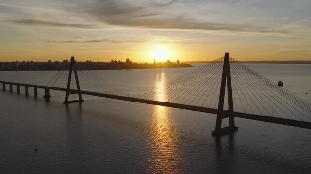 Panoramic drone view of international bridge and Posadas skyline at sunset.