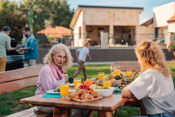 Family enjoying lunch in the garden while chefs are grilling meat