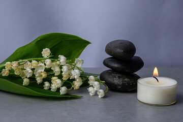 Relaxing spa arrangement with flowers, stones, and a lit candle for tranquility