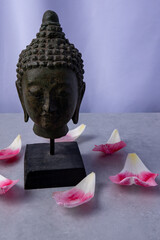 Buddha sculpture surrounded by flower petals on a serene surface
