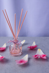 Fragrant diffuser surrounded by pink petals on a serene surface