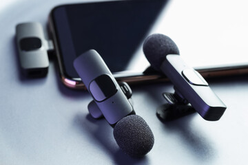 Lavalier microphones and smartphone on light grey background, closeup