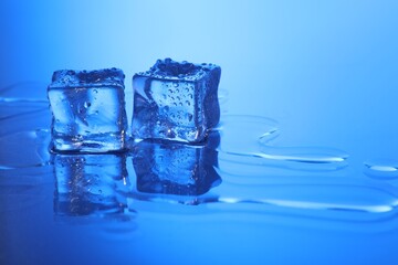 Cubes of clear ice on light blue background, space for text