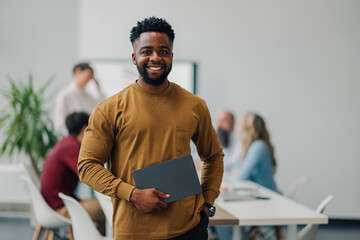Smiling black manager holding tablet during office meeting