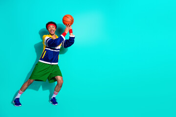 Energetic young man in vibrant retro sportswear gearing up for a basketball game against teal backdrop