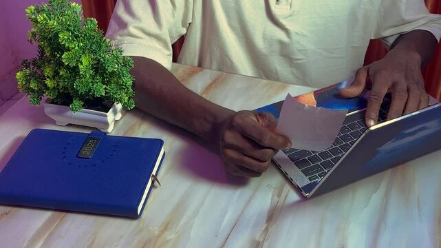 hand holding payment bill slip while updating online using laptop