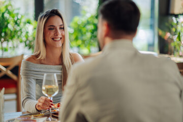 Smiling woman enjoying romantic lunch with man in restaurant