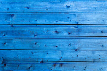 Obraz premium Horizontal planks of wood painted in bright blue with visible grain and knots in natural light.