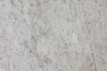 Close-up of a light gray marble surface with scratches and natural veining, perfect for backgrounds, architecture, or design mockups