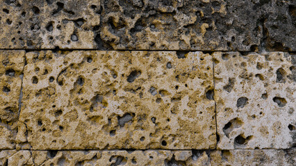 Close-up of a weathered limestone wall with porous surface and natural erosion, ideal for architectural, geological, or historical design themes.