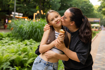 Obraz premium Mom and daughter walk in the park and eat ice cream