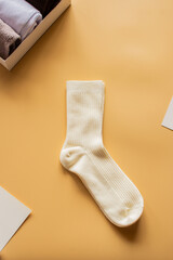 Soft cream colored sock pair placed on warm yellow background. Ideal for comfort wear promotions, sock collections, or joyful lifestyle imagery. Vertical.