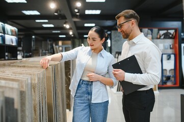 Woman choosing ceramic tiles with shop assistant advising her