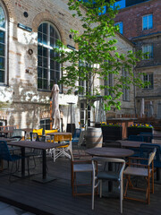 Outdoor modern cafe terrace with colorful chairs and tables in a sunny urban courtyard