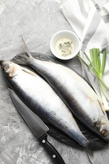 Salted herrings, spices and knife on grey table, flat lay