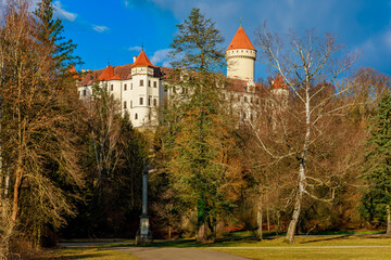 Fototapeta premium Majestic medieval castle with red turrets surrounded by autumn forest