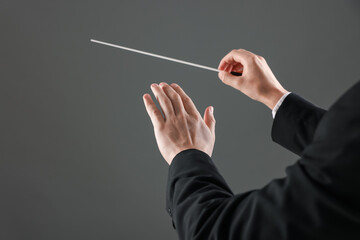 Professional conductor with baton on grey background, closeup