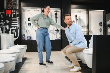 Fototapeta premium Couple having fun choosing toilet in bathroom furniture store