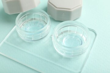 Contact lenses in case on light turquoise background, closeup
