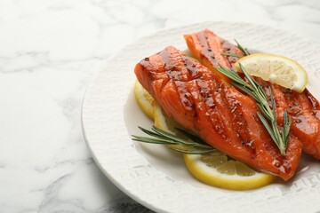 Seafood. Tasty grilled salmon served with rosemary and lemon on white marble table, closeup. Space for text