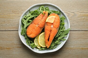 Seafood. Tasty salmon steaks, arugula and lemon on wooden table, top view