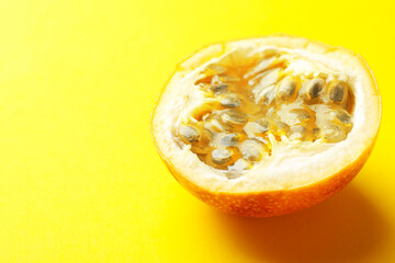 Piece of ripe passion fruit on yellow background, closeup. Space for text