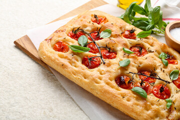 Delicious focaccia with tomatoes and spices on beige textured table, closeup