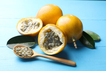 Ripe passion fruits, green leaves and seeds on light blue wooden table, closeup