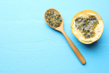 Ripe passion fruit and seeds on light blue wooden table, flat lay. Space for text