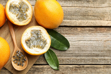 Ripe passion fruits, seeds and leaves on wooden table, flat lay. Space for text