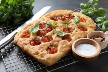 Delicious focaccia with tomatoes, spices and knife on table, closeup