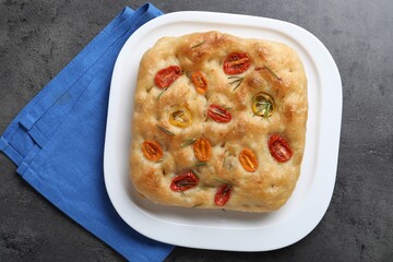 Delicious focaccia with tomatoes and rosemary on gray textured table, top view