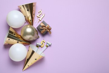 Beautiful party hats and other festive decor on violet background, flat lay. Space for text