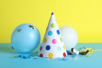 Beautiful party hat and other festive decor on color background
