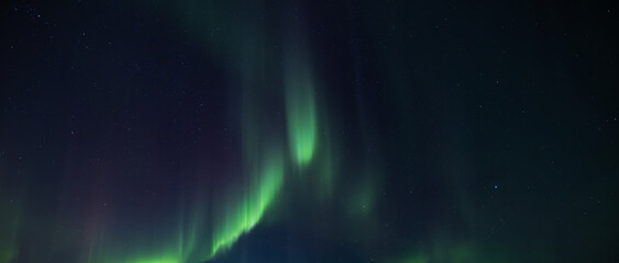 Fairy winter mountains with snowy fir-trees and incredible Northern lights in starry sky. Christmas...