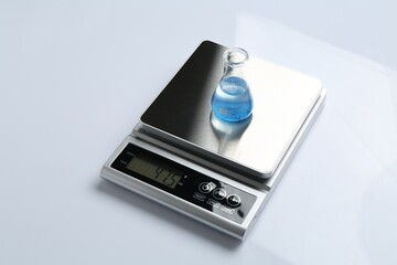 Laboratory scale with flask of sample on white background