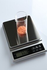 Laboratory scale with beaker of sample on white background, above view