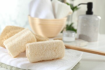 Different loofah sponges and towels on white table, closeup