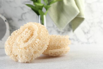 Different loofah sponges on light grey table, closeup. Space for text