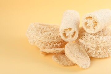 Different loofah sponges on beige background, closeup. Space for text