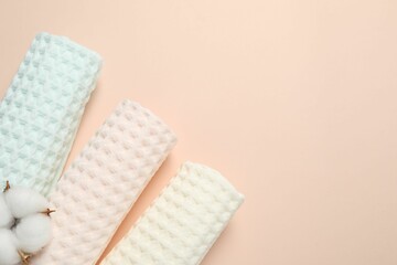 Clean waffle towels and cotton flower on beige background, flat lay. Space for text