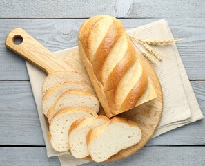 Cut loaf of bread and spikes on grey wooden table, top view