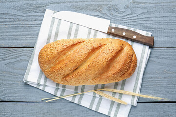 Loaf of bread, knife and spikes on grey wooden table, top view